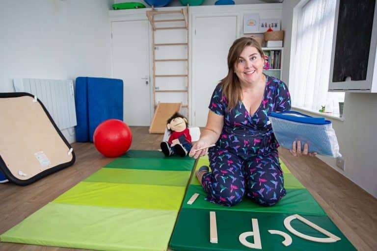 Amy kneeling in the therapy room of Super Kids Therapy HQ